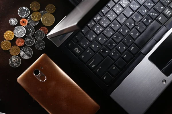 Laptop, Münzen und ein Smartphone — Stockfoto