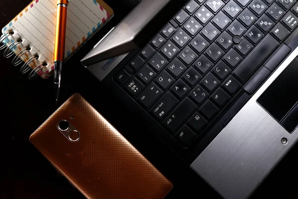 Computador portátil, caneta, notebook e um smartphone — Fotografia de Stock