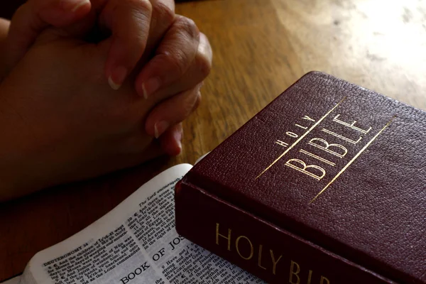 Holy Bible on a table and hands in praying position