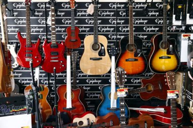 Çeşitli akustik ve elektrik gitarları bir müzik mağazasında sergileniyor.