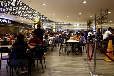 Müşteriler yemeklerini ticari bir alışveriş merkezinin yemek salonunda yiyor.