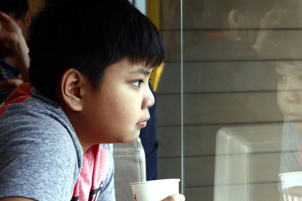 Young Asian boy drink from a paper cup inside a fast food restaurant — Stock Photo, Image