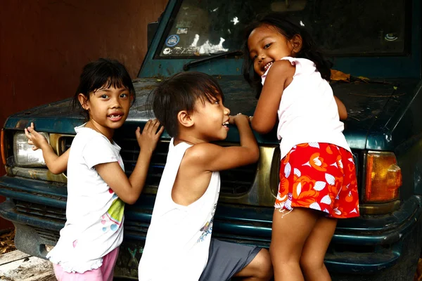 若いフィリピンの子供たちは駐車中の車で遊び、カメラのために笑顔. — ストック写真