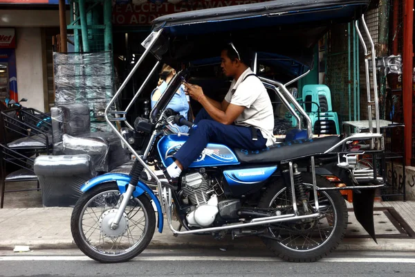 Üç tekerlekli bisiklet sürücüsü yolcu beklerken dinleniyor ve akıllı telefon kullanıyor. — Stok fotoğraf