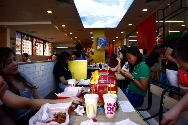 Los clientes disfrutan de su comida en el interior internacionalmente conocido restaurante de comida rápida . — Foto de Stock