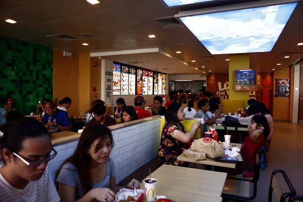 Los clientes disfrutan de su comida en el interior internacionalmente conocido restaurante de comida rápida . — Foto de Stock