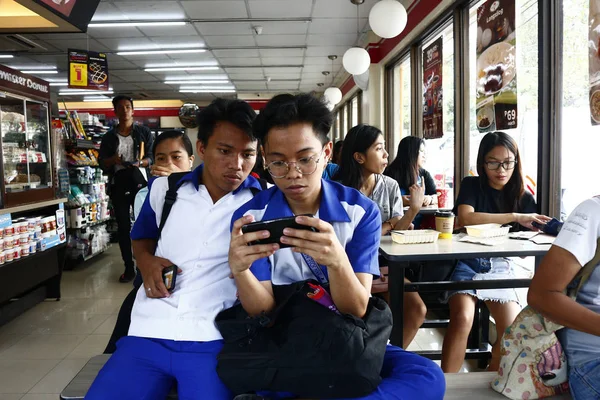 Adolescentes filipinos descansam na loja conveniente e jogam videogame no smartphone — Fotografia de Stock