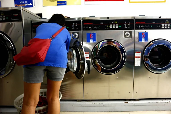 Le client met des vêtements sales à l'intérieur de la machine à laver au magasin de blanchisserie libre-service ou laverie automatique . — Photo