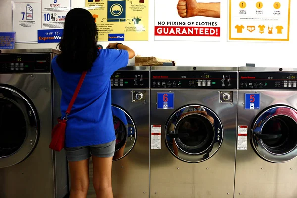 Le client met des vêtements sales à l'intérieur de la machine à laver au magasin de blanchisserie libre-service ou laverie automatique . — Photo