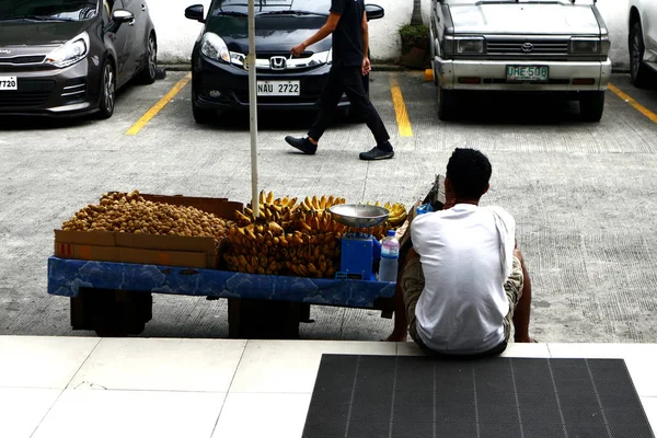 Fruktförsäljare som säljer bananer och lanzoner vilar på trottoaren — Stockfoto