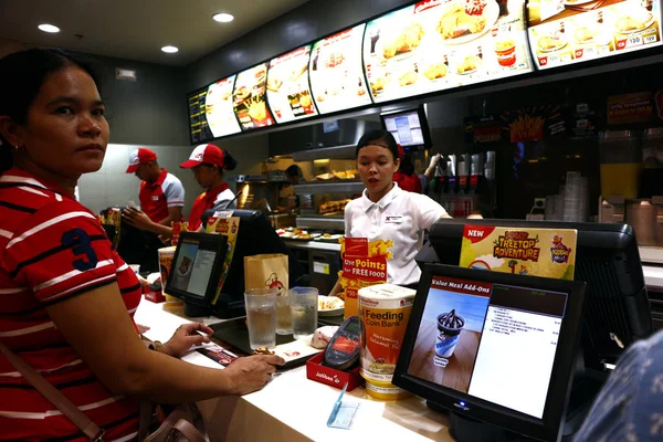 Empregado de restaurante de fast food bem conhecido serve comida no balcão para o cliente . — Fotografia de Stock