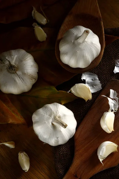 Verse knoflook op keukentafel en houten lepel — Stockfoto