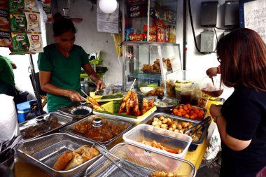 Yemek tezgahındaki sokak yemekleri satıcısı müşteriye çeşitli abur cuburlar satıyor..