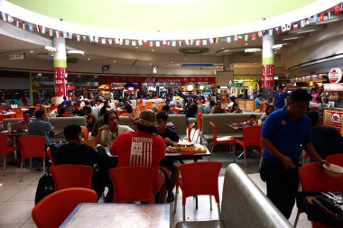 Customers eat their meal at a food court inside a commercial shopping center. clipart