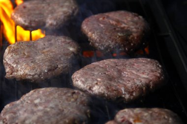 Taze hamburger köftelerinin ateşte kızardığı bir fotoğraf..