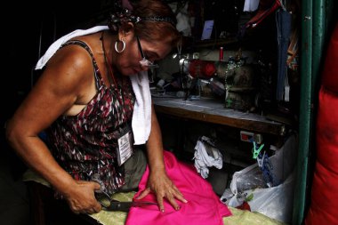 Antipolo Şehri, Filipinler - 1 Haziran 2020: Terzi, bir elbise terzisinde endüstriyel dikiş makinesi olan bir elbisenin bir parçasını diker.
