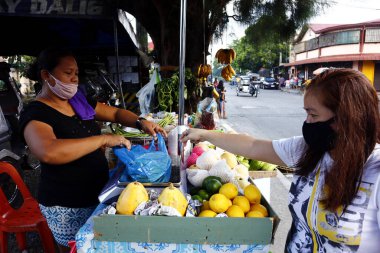 Antipolo Şehri, Filipinler - 9 Haziran 2020: Müşteri kaldırım kenarındaki derme çatma tezgahındaki bir satıcıdan taze meyve ve sebze satın alır.