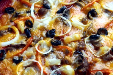 Domates soslu, peynirli, siyah zeytinli, soğanlı, jambonlu, mantarlı ve pepperonili yeni yapılmış pizzanın yakın plan fotoğrafı..