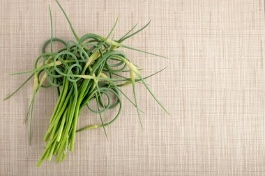 Bir grup genç yeşil sarımsak okları ışık tekstil peçete. Üstten görünüm