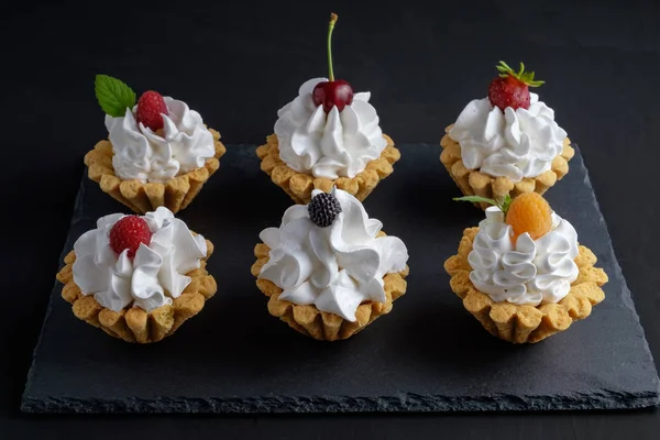 Protein krem ve siyah arka plan üzerinde koyu taş plaka üzerinde yaz meyveleri ile altı kek. Yakın çekim görünümü