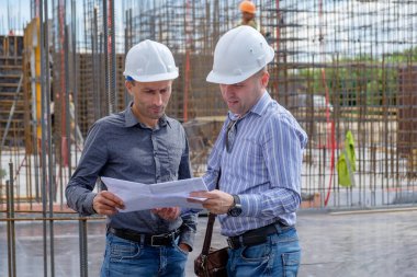 Foreman ve Yüklenici inşaat alanına projede bakıyorsun. Ekip çalışması kavramı.