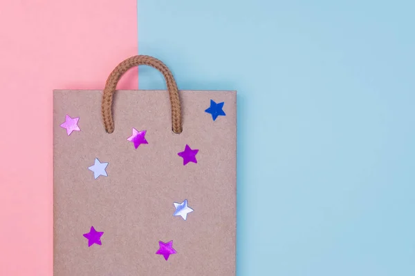 Craft paper shopping bag with stars on paper textured backdrop. Use copy space for sale and store design. Consumer concept.