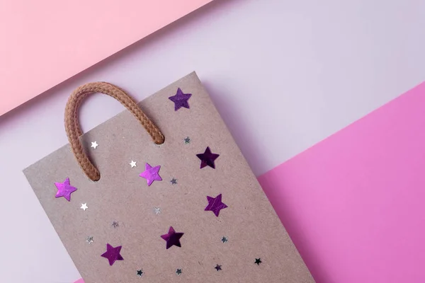 Craft paper shopping bag with stars on paper textured backdrop. Use copy space for sale and store design. Consumer concept.