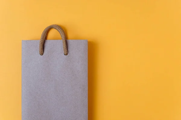 Craft paper shopping bag on yellow paper background. Store and sale concept.