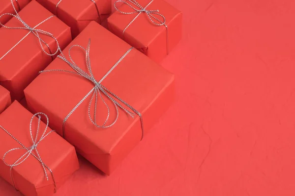 プレゼントのヒープは赤いクラフト紙に包まれ 赤の背景に銀の糸と結ばれます 領域をコピーします お祭りイベントと Selebrations のコンセプトは します — ストック写真