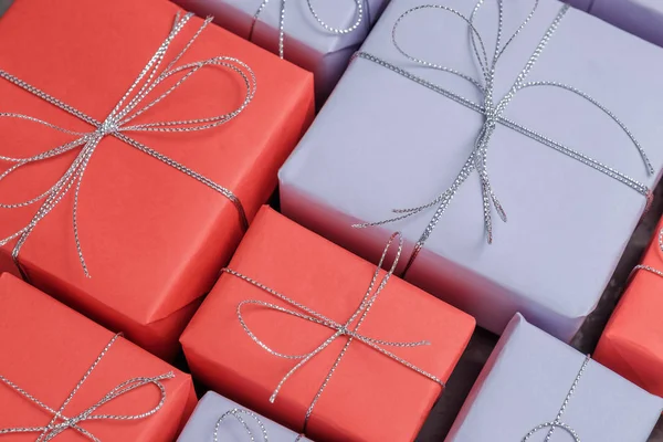 たくさんのお祝いプレゼントは赤と薄紫色の紙に包まれた 銀ひもと結ばれます 驚きを作るためのギフト クローズ アップ トップ ビュー — ストック写真