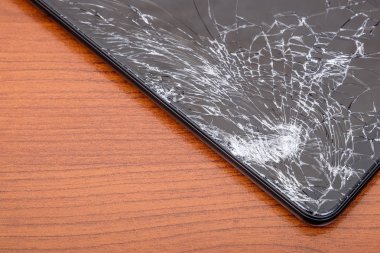 Siyah ahşap arka plan üzerinde kırık dokunmatik ekrana sahip akıllı telefon. Yakın çekim görünümü. Mobil cihazların bakım ve onarım kavramı