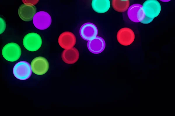 Blurred color bokeh circles. Abstract festive lights background on black
