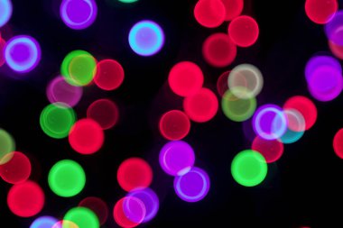Parti ışıkları siyah arka plan bulanık. Çok renkli festival bokeh daireler 