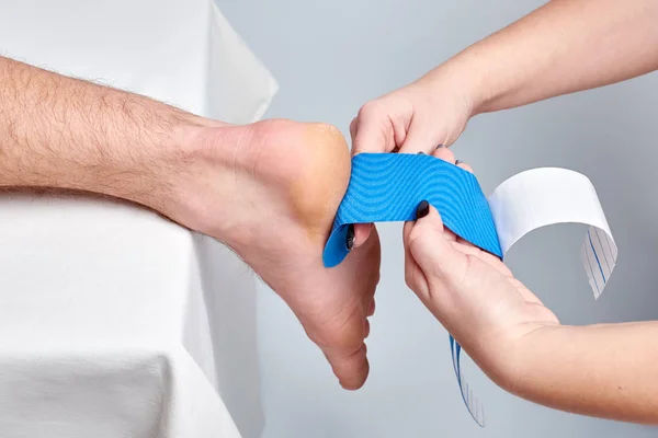 Doktor fizyoterapist uygulanan kinesio tıbbi bir beyaz adam bileğinde taping eller. Closeup görünümü