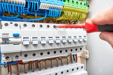 Otomatik devre kesiciler ile geçiş panosu. Dielektrik tornavida elektrikçi elinde. Arka plan ve doku