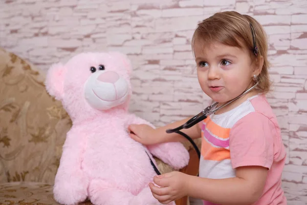 Lindo niño jugando médico o enfermera con juguetes de peluche en casa . — Foto de Stock