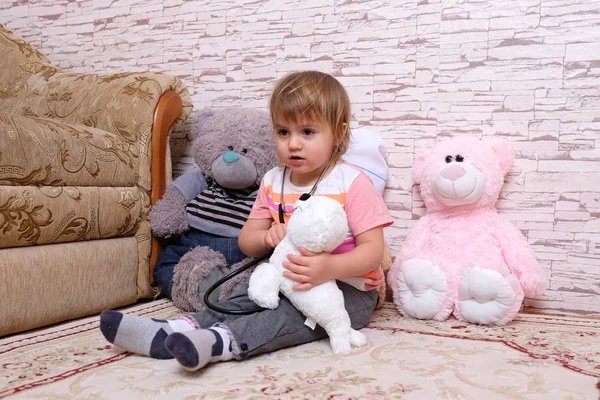Милый ребенок, играющий в доктора или медсестру с плюшевыми игрушками дома . — стоковое фото