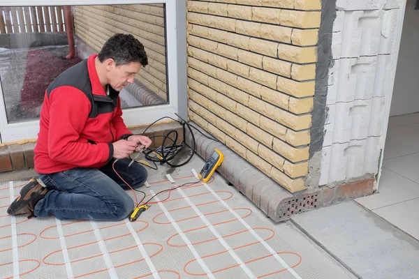 Eletricista instalando aquecimento cabo elétrico no floo de concreto — Fotografia de Stock