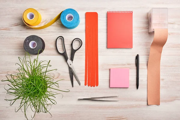 Maqueta con cuaderno, pegatinas, rollos de cinta de color kinesio, tijeras, pinzas y otras herramientas — Foto de Stock