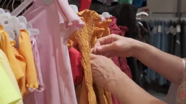 Gros plan femmes mains cueillies un cintre avec des vêtements . — Video