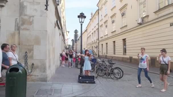 Kraków Polska-08.24.2019: młoda dziewczyna gra na skrzypcach dla turystów na ulicy starego miasta — Wideo stockowe