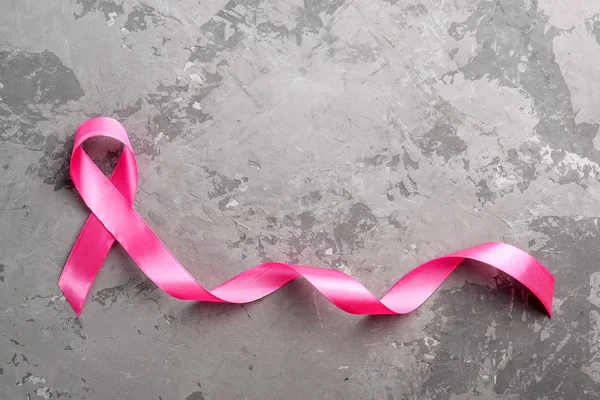 Roze lint op een betonnen ondergrond. Borstkanker bewustzijn maand — Stockfoto
