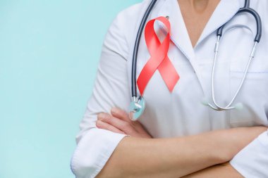 Doctor with folded arms and a stethoscope on his neck, shows a red ribbon close-up on uniform