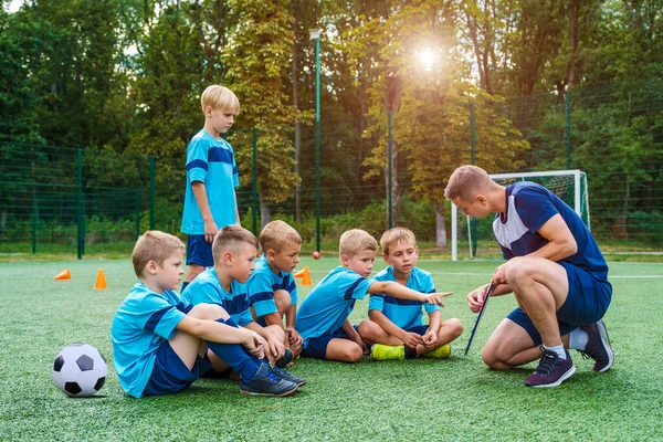 Genç koç küçük çocuklara futbol sahasında oynama stratejisini öğretiyor.. 