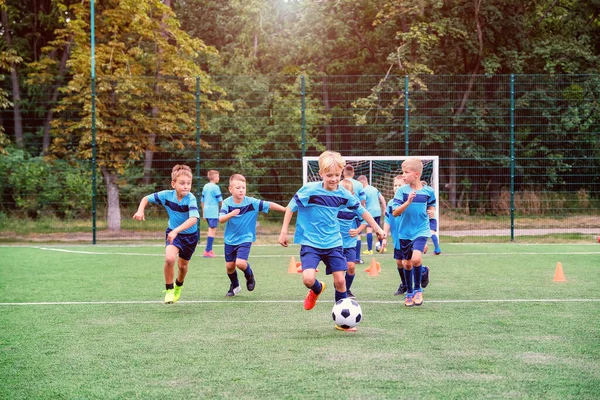 Niños corriendo y pateando pelotas de fútbol en la sesión de entrenamiento de fútbol infantil —  Fotos de Stock