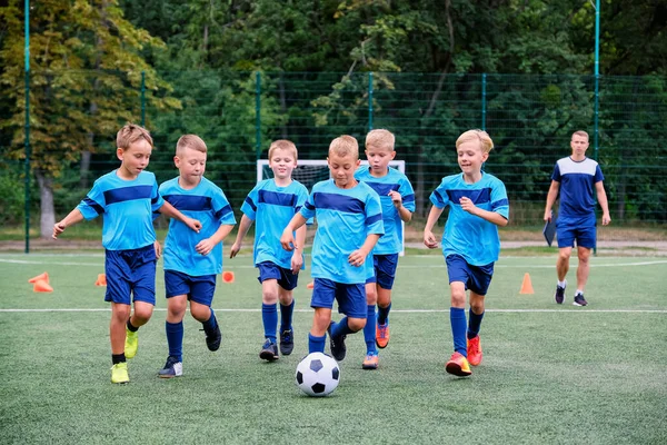 Діти бігають і штовхають футбольний м'яч на тренуваннях дітей футболу — стокове фото