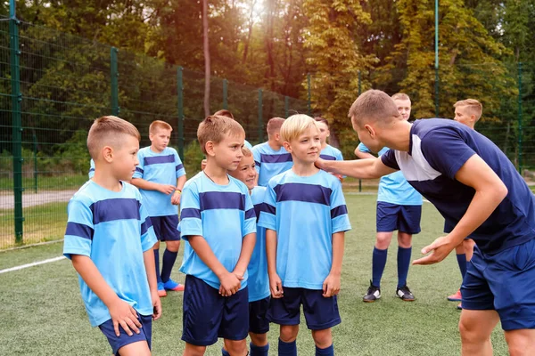 Děti ve fotbalové uniformě poslouchají vysvětlování trenéra před zápasem. — Stock fotografie