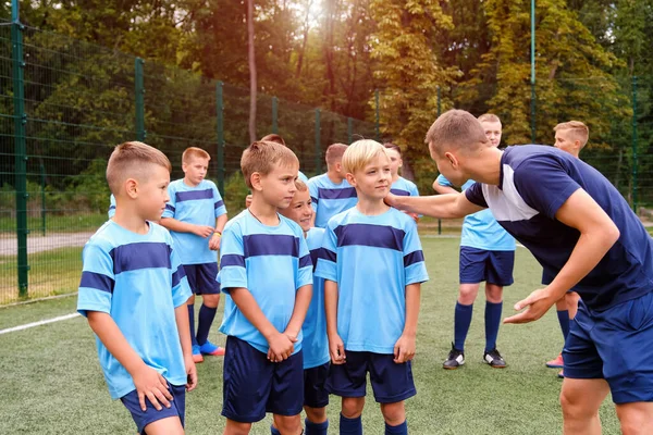 Futbol formalı çocuklar maçtan önce koçun açıklamasını dinliyorlar..