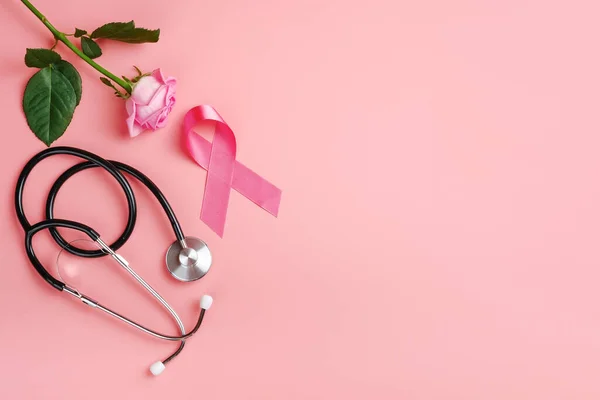 Pembe kurdele, pembe arka planda gül ve steteskop. Göğüs kanseri farkındalığı 