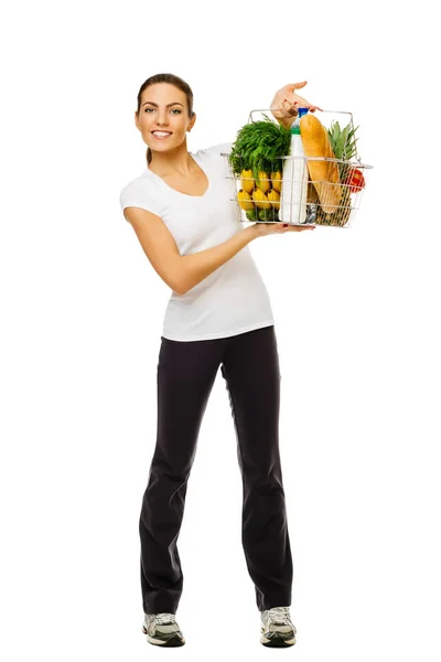 Joven chica morena deportiva sosteniendo cesta de comida, frutas y verduras frescas. En pleno crecimiento. sobre fondo blanco —  Fotos de Stock